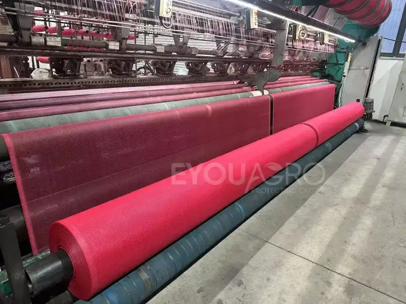 a loom at the eyouagro factory weaving vibrant red shade netting.