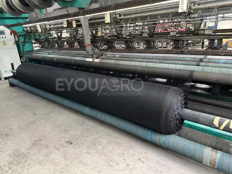 Heavy-duty black anti-hail netting being produced on a loom at the EyouAgro factory.