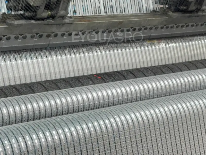 A close-up of a finished roll of Aluminet screen, showing its premium knitted texture and reflective strips.
