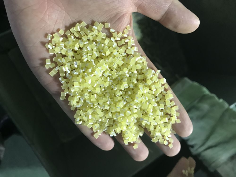 A handful of pale yellow anti-UV masterbatch granules
