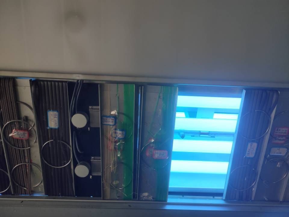 Inside the QUV chamber — UV lamps lit with netting samples clamped on both sides